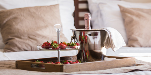 Schaal met champagne op een bed, met aardbeien